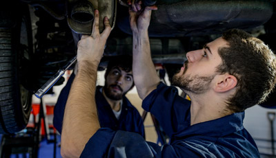 A student checking the play of a car's suspension