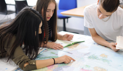 3 Students looking at a map of the world