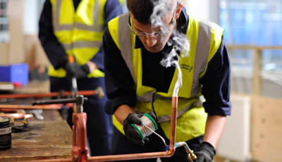 Plumbing students soldering copper pipe
